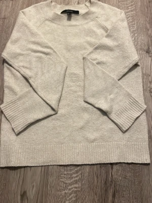 Ljusgrå stickad tröja  - En stilren ljusgrå stickad tröja från H&M med rund halsringning och ribbade muddar vid ärmslut och nederkant. Perfekt för lager-på-lager och enkel att matcha med olika outfits. Mjuk och bekväm känsla.