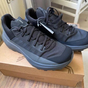 Arc'teryx Norvan LD 4 - Helt oanvända Arcteryx Norvan LD 4, nypris ligger på 1999 kr.                                              Snygga svarta sneakers från Arc'teryx med låg profil och robust vibram sula. Skorna har en stilren design med mesh- och syntetmaterial, samt matchande svarta skosnören. Perfekta för dig som gillar en clean och sportig look. 