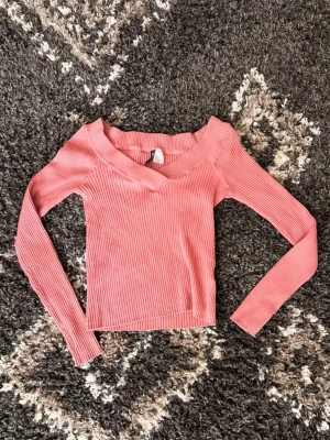 Rosa ribbad topp från Divided H&M - Säljer en snygg rosa ribbad topp från Divided H&M. Tröjan har lång ärm, djup v-ringning. Strl Xs