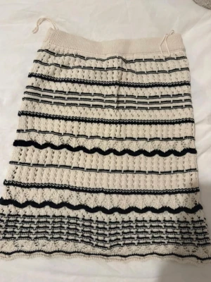 Randig stickad kjol från Vero Moda - Supersöt stickad kjol från Vero Moda i beige och svart med randigt mönster och vågiga detaljer. Kjolen har resår i midjan och är i en mjuk, stickad kvalitet som ger en chill och trendig vibe.