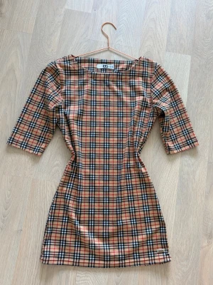 Rutig kortklänning från GARZIA Italia  - Kortklänning från märket Garzia Italia med rutmönster i burberry-inspirerad stil. Garzia Italia är ett klädmärke etablerat i Italien som säljer dammode med mer inriktat på kvalité, moderna snitt med fokus på elegantkoordinerade set för kvinnor som vill kombinera komfort och stil. Obs: det är inte burberry dock utan burberry inspirerat. Säljer för att den är för liten på mig. 