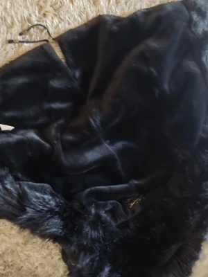 Svart pälsjacka från Attentif Paris - Säljer en svart pälsjacka från Attentif Paris Parka Collection i storlek 36. Jackan har en lyxig, glansig finish och mjuk fuskpäls som ger en elegant look. Perfekt för kalla vinterdagar när du vill hålla dig varm och snygg.