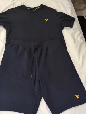 Mörkblå dress  från Lyle & Scott helt ny  - Snygga mörkblå shorts från Lyle & Scott med klassisk gul logga på benet. Shortsen har snörning i midjan för skön passform och är gjorda i mjuk bomull, perfekta för sommardagar. Enkel och stilren design som funkar till det mesta. Dress helt ny 799