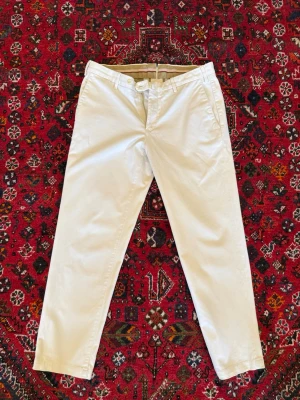 Loro Piana Chinos - Loro Piana Chinos i krämvit färg. Perfekta plagget inför sommaren som funkar dagligen men även till mer formella tillställningar. Byxorna är gjorda av 98% bomull | 2% elasten. Nypris runt 10000kr.