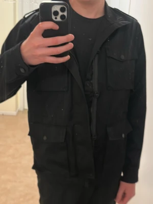 Svart feildjacket  - Säljer en svart feildjacket från On our Terms. Köpte den från ellos för cirka ett år sen för 1000kr och har bara använt den typ 2 gånger. Den är perfekt att ha på vår/ höst eller lite kyliga sommarkvällar