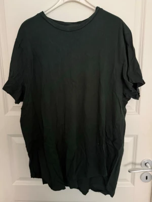 Mörkgrön basic t-shirt i bomull - En enkel mörkgrön t-shirt med rund hals och korta ärmar. Tillverkad i mjuk bomull och har en loose passform. Perfekt för en avslappnad och stilren look.