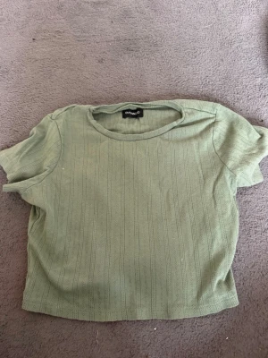 Grön ribbad topp från Even&Odd - Snygg grön ribbad topp från Even&Odd. Toppen har en enkel och stilren design med rund halsringning och är tillverkad i ett mjukt material som känns skönt mot huden. Perfekt att matcha med jeans eller kjol för en trendig look.
