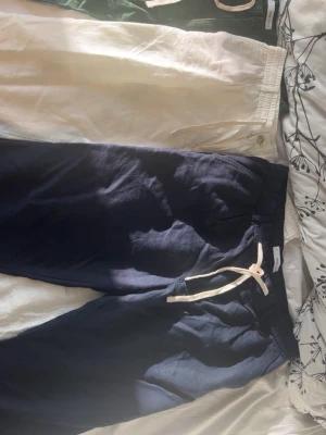 Linnebyxor i marinblått, vitt och grönt - Tre par linnebyxor i marinblå, vit och grön färg. Alla har avslappnad passform, resår i midjan och dragsko för skön och justerbar känsla. Perfekta för chill dagar och sommarhäng. Materialet är svalt och luftigt linne. Storlek 44 typ M