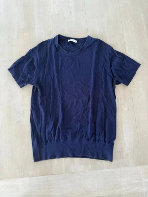 Mörkblå basic t-shirt - En enkel mörkblå t-shirt med rund hals och korta ärmar. T-shirten har en bred ribbad kant nedtill som ger en snygg passform. Perfekt till jeans eller shorts för en clean look.