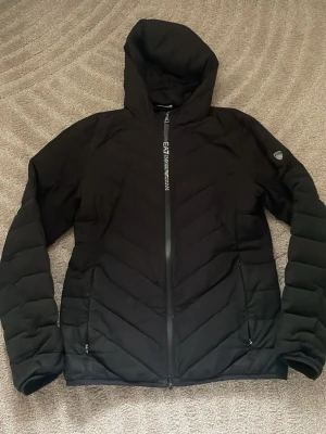 Svart pufferjacka från Emporio Armani - Svart pufferjacka från Emporio Armani EA7. jackan har stora fickor på insidan med. 