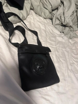 Svart axelväska från Just Cavalli - Snygg svart axelväska i läder från Just Cavalli. Köpte den i Spanien för 1,2 och det är i jätte bra skicka eftersom jag inte använde den så mycket.