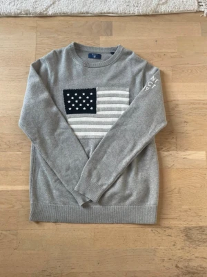 Grå gant tröja - GANT grå tröja med USA-flagga – fint skick   Säljer en snygg grå GANT-tröja med broderad USA-flagga på bröstet. Klassisk modell som passar till både vardag och lite finare tillfällen.  • Märke: GANT • Färg: Grå • Skick: Bra skick, inga hål eller fläckar • Storlek: S  Nypris runt ca 1200–1700 kr. Säljes för 349 kr eller vid snabb affär.  Skickar snabbt