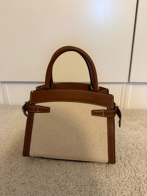 Beige/ brun handväska  - Stilren handväska! I helt nytt skick. Finns band till. 