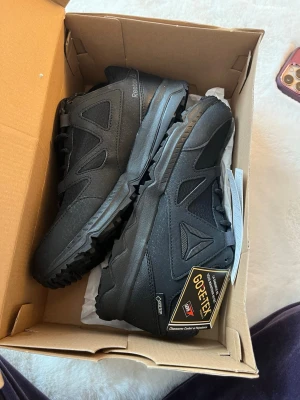 Svarta Reebok sneakers med Gore-Tex - Svarta sneakers från Reebok med slitstark ovandel i textil och syntet, samt vattentätt Gore-Tex-membran. Snygg design med Reebok-logga på sidan och grov sula för extra grepp. Perfekta för dig som vill ha stilrena och funktionella skor.