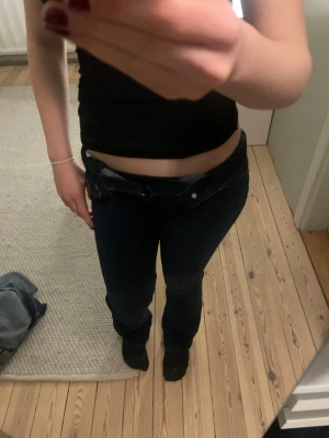 Mörkblå bootcut jeans - Säljer ett par mörkblå bootcut jeans med låg midja. Jeansen har dragkedja och knapp framtill. Perfekta för dig som gillar en tidlös och snygg look.