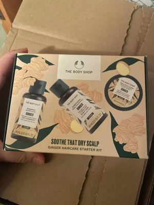 The Body Shop Ginger Haircare Kit - Ginger Haircare Starter Kit från The Body Shop med schampo, balsam och hårmask. Produkterna innehåller ingefäraextrakt och är veganska. Perfekt för dig som vill lugna torr hårbotten. Förpackningen är beige med gröna och gula detaljer.