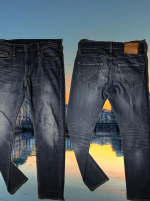Levi's 502 mörkblå jeans - Snygga mörkblå jeans från Levi's modell 502 med klassiska fem fickor och läderpatch bak. Jeansen har en rak passform och subtila slitningar för en cool look. Perfekt för dig som gillar tidlös denimstil.