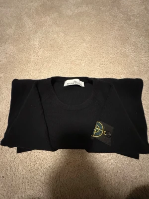 Svart stickad Stone Island tröja - Svart stickad tröja från Stone Island med rund hals och den klassiska logotypen på ärmen. Tröjan har en clean och tidlös design, perfekt för dig som gillar streetwear och vill ha något som sticker ut med exklusiv känsla.Den är köpt direkt från hemsidan för ungefär 2,5 år sedan därför kommer den utan box.KAN DISKUTERA PRIS!!!