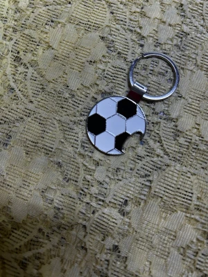 Fotboll flasköppnare Nyckelring  - Säljer en rund nyckelring i metall med flasköppnare med ett svartvitt fotbollsmotiv. 