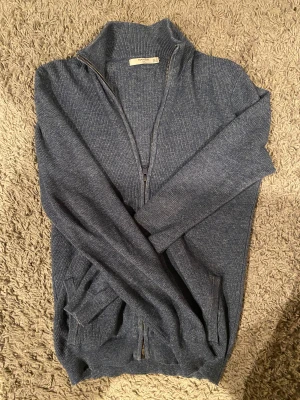 Mörkblå stickad kofta från Mango - Snygg mörkgrå stickad kofta från Mango med ribbad struktur och hel dragkedja framtill. Koftan har hög krage och långa ärmar, perfekt för lager-på-lager. Passar dig som gillar enkel och stilren design.