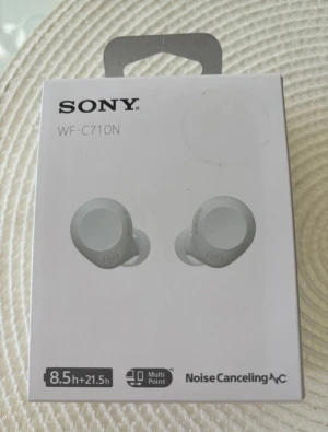Sony WF-C710N trådlösa in-ear hörlurar - Säljer ett par vita Sony WF-C710N trådlösa in-ear hörlurar med aktiv brusreducering och lång batteritid på upp till 8,5 timmar (totalt 21,5 timmar med laddningsfodral). Kompatibla med både iPhone och Android samt stöd för Spotify Tap och multipoint-anslutning.(aldrig använt,öppet endast för fotot)