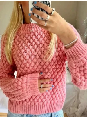 Rosa bubblig stickad tröja - Superfin rosa stickad tröja med bubbligt strukturmönster och ribbade muddar vid ärmslut, hals och nederkant. Storlek S och år i bra kvalité! Första bilden är tagen, men andra är min.