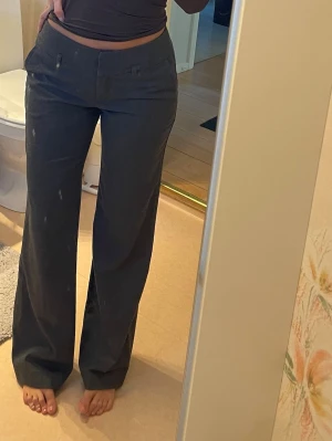 Mörkgrå vida kostymbyxor - Säljer mörkgrå kostymbyxor med låg midja och vida ben. Jag är 170cm lång 