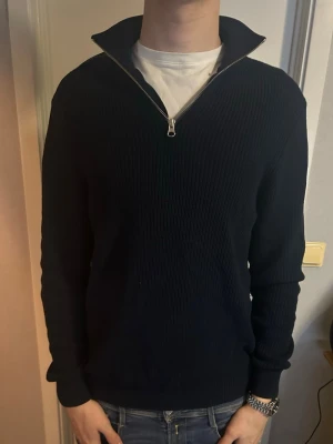 Marinblå ribbstickad halvzip-tröja - Marinblå ribbstickad tröja med halvzip och hög krage. Schysst med en skjorta under. Strlk M. Köpt ifrån Zara. Gott skick. Pris går att diskutera.