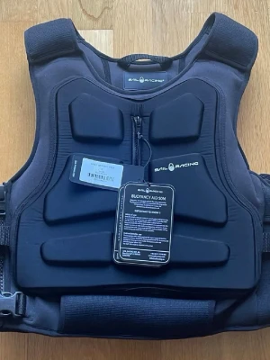 Svart flytväst Sail Racing - Säljer en svart flytväst från Sail Racing med coolt, sportigt utseende och vadderade paneler. Västen har dragkedja framtill, justerbara remmar i sidan och Sail Racing-logga både fram och bak. Perfekt för segling eller andra vattenaktiviteter. Nypris 3000:-