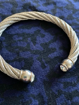 Silvrigt tvinnat armband med kristaller - Joan Rivers armband i silvrig metall med tvinnad design. Öppna ändar med runda detaljer och infattade klara kristaller. Stilren och modern look som passar till många outfits.