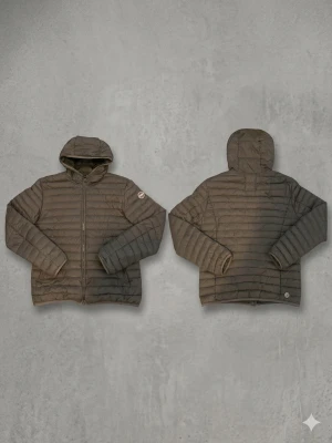 Colmar Dunjacka - Snygg brun dunjacka från Colmar med quiltad design och fast huva. Jackan har dragkedja framtill, två sidofickor och diskret logga på ärmen. Perfekt för kalla vinterdagar och ger en stilren look.Är svart med brun nyans. Kostar runt 3000kr nypris