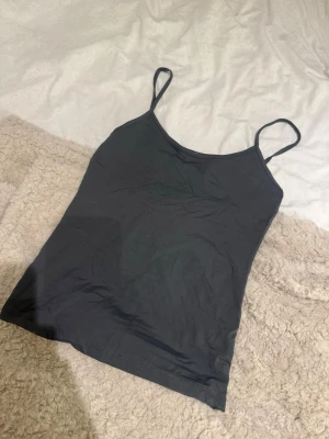 Mörkgrå linnetopp från Zara - En enkel och stilren mörkgrå linnetopp från Zara med tunna axelband. Perfekt att matcha med jeans eller kjol för en clean look. Tillverkad i mjuk bomull som känns skön mot huden.