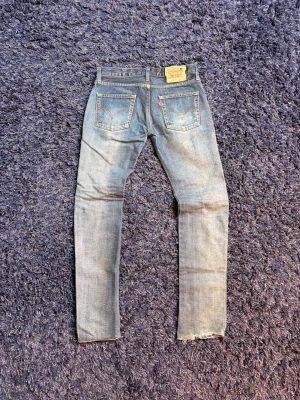 Levi's jeans - Säljer ett par klassiska ljusblå jeans från Levi's med raka ben och femficksmodell. Jeansen har en vintage tvätt och den ikoniska läderlappen bak i midjan. Tillverkade i slitstark denim med snyggt slitna detaljer och Levi's röda etikett på bakfickan. Dessa är i hårdare denim så de är inte lika töjbara som vissa andra jeans. Hör av er vid minsta fundering!