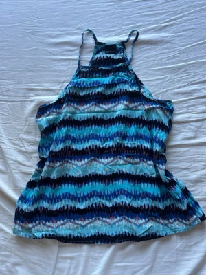Blåmönstrad linnetopp från Gina Tricot - Säljer en snygg linnetopp från Gina Tricot med blått, svart och vitt zigzagmönster. Missoni liknande mönster. Toppen har smala axelband och är ärmlös