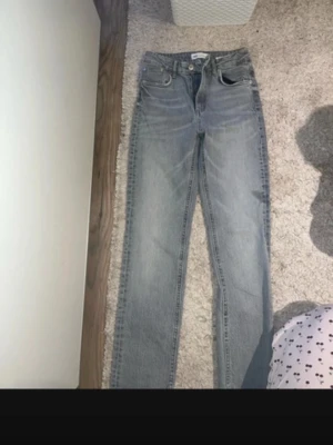 Grå raka jeans med slits nertill - Snygga grå jeans med raka ben och slits nertill på benen. Jeansen har klassisk femficksmodell och normalhög midja. Perfekta för en avslappnad och trendig look.