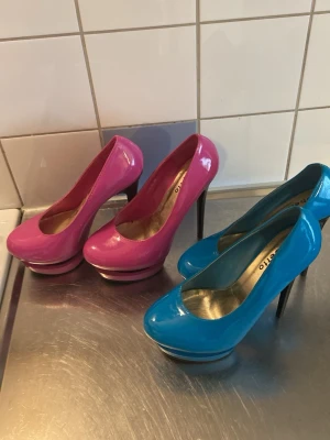 Färgglada pumps från Roberto - Två par glansiga pumps från Roberto, ett par i knallig rosa och ett par i klarblått. Skorna har hög platåsula och stilettklack, rundad tå och lackad finish som ger en riktigt poppig look.