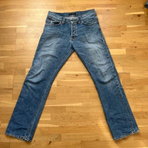 Nudie Jeans Average Joe  - Säljer ett par klassiska blå jeans från Nudie Jeans med rak passform och fem fickor. Jeansen har en snygg tvättad look. Strl W32 L34