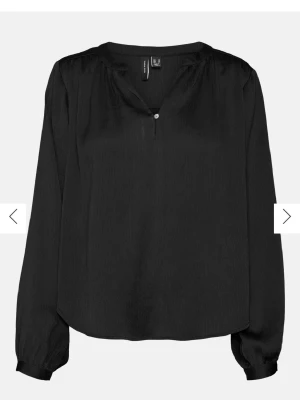 Svart blus från Vero Moda med knapp - Stilren svart blus från Vero Moda med lätt glansigt tyg och diskret struktur. Blusen har en liten V-ringning med knapp framtill och långa ärmar med breda muddar. Perfekt att matcha med jeans eller kjol för en trendig look.