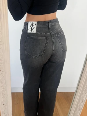 Calvin Klein Jeans  - Säljer ett par supersnygga high waisted straight leg grå jeans från Calvin Klein. Mina föredetta favoritjeans då de sitter sjukt snyggt baktill, men de kommer tyvärr inte till användning längre. Storlek W27. Bra skick, lite slitna i bensluten, har en liten fläck baktill 💕