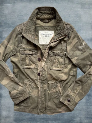 Abercrombie & Fitch Camo Fieldjacket - En mycket trevlig fieldjacket från Abercrombie & Fitch i ett extremt snyggt camo mönster! Modellen är 178 cm och väger 68 kg. Hör av dig vid frågor! 