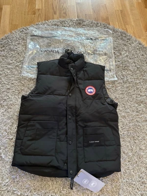Svart dunväst från Canada Goose - Snygg svart dunväst från Canada Goose med hög krage, HELT NY XXL Passar Xl, skriv för fler bilder. Mått kan skickas och priset kan såklart diskuteras 