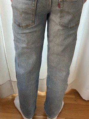 Levi's raka ljusblå jeans - Säljer ett par klassiska raka jeans från Levi's i ljusblå denim. Jeansen har fem fickor, normal midja och subtila slitningar för en avslappnad look. Perfekta till sneakers och hoodie för en chill stil.