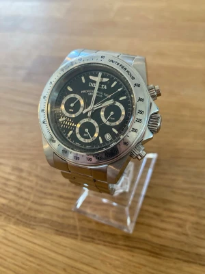 Invicta Pro Speedway 40mm Herrklocka - Säljer en ursnygg något ovanlig Invicta Herrklocka i nära nyskick enligt bilder. Coolt streckat mönster i urtavlan vilket inte ska tolkas som repor. Finns enstaka tecken på användning som knappt syns eller stör. Fungerar utmärkt med helt nytt batteri, originalarmband i stål, datumvisare, mineralglas, japanskt urverk, vattentät till 200 meter, kronograf osv. Modell: 9223.  Nypris: 2150 SEK Mitt pris: 789 SEK  Skickas snabbt och spårbart. Fråga på och se gärna mina andra annonser!