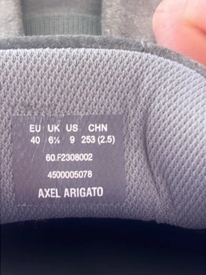 Grå slip-on sneakers Axel Arigato - Snygga grå slip-on sneakers från Axel Arigato i textilmaterial. Skorna har en minimalistisk design utan snörning och en stilren siluett som passar till många olika outfits. Levereras med originalkartong och dustbag.