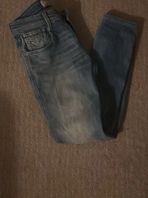 Blå jeans från Replay - Säljer ett par Snygga blå jeans från replay i modellen anbass, dom är använda ett tag men har hållit bra de enda är fickan som e sönder fast du kan ha grejer i fickan!. Dm för mer information 