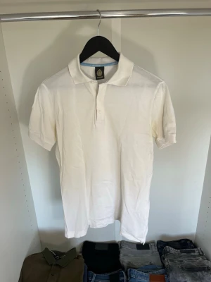 Vit pikétröja från Dondup - Klassisk vit pikétröja från Chintong med krage och korta ärmar. Tröjan har knäppning framtill med två knappar och är tillverkad i ett mjukt bomullsmaterial. Hör gärna av dig vid frågor!