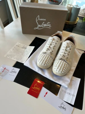 Vita Christian Louboutin sneakers med nitar - Säljer mina stilrena Christian Louboutin sneakers då jag tröttnat på de, perfekt nu inför sommaren, skicket är bra behövs bara tvätt, de är i storlek 43, pris går självklart diskutera! 🤍❤️