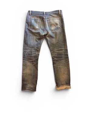  A.P.C. Selvage jeans - Snygga blå jeans från A.P.C. med slitningar och patch på ena benet. Klassisk femficksmodell, raka ben och uppvikta benslut. Jeansen har en cool tvättad look och tydliga whiskers vid knäna. Perfekta för en avslappnad streetstil.