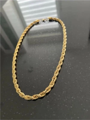 Guldfärgat tvinnat halsband - Snyggt halsband i guldfärg med tvinnad kedja som ger en cool och trendig look. Perfekt accessoar för att lyfta din outfit. Halsbandet har ett klassiskt lås och är gjort i metall.