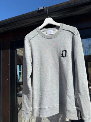Grå sweatshirt från Dondup - Snygg grå sweatshirt från Dondup med svart broderad D på bröstet. Perfekt för en avslappnad och stilren look. Fräsch och sällan använd! Inga defekter eller märken. Skriv vid frågor!
